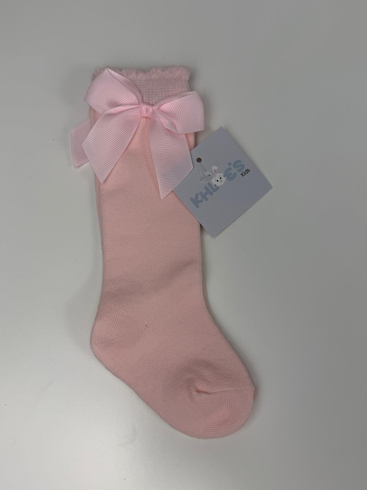 Pink knee-high sock with a large bow on a gray background