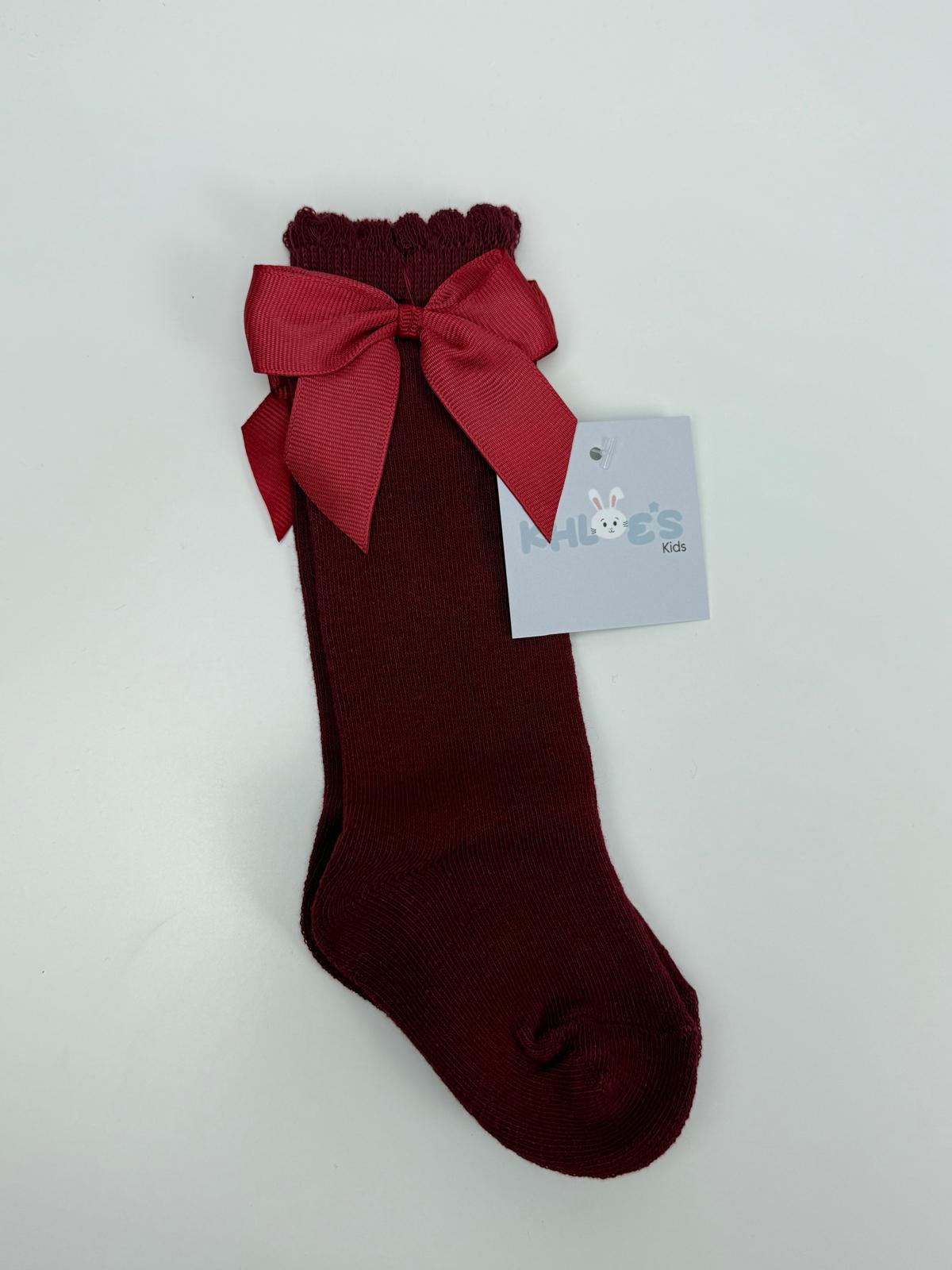 Maroon sock with a large red bow and a tag on a light gray background