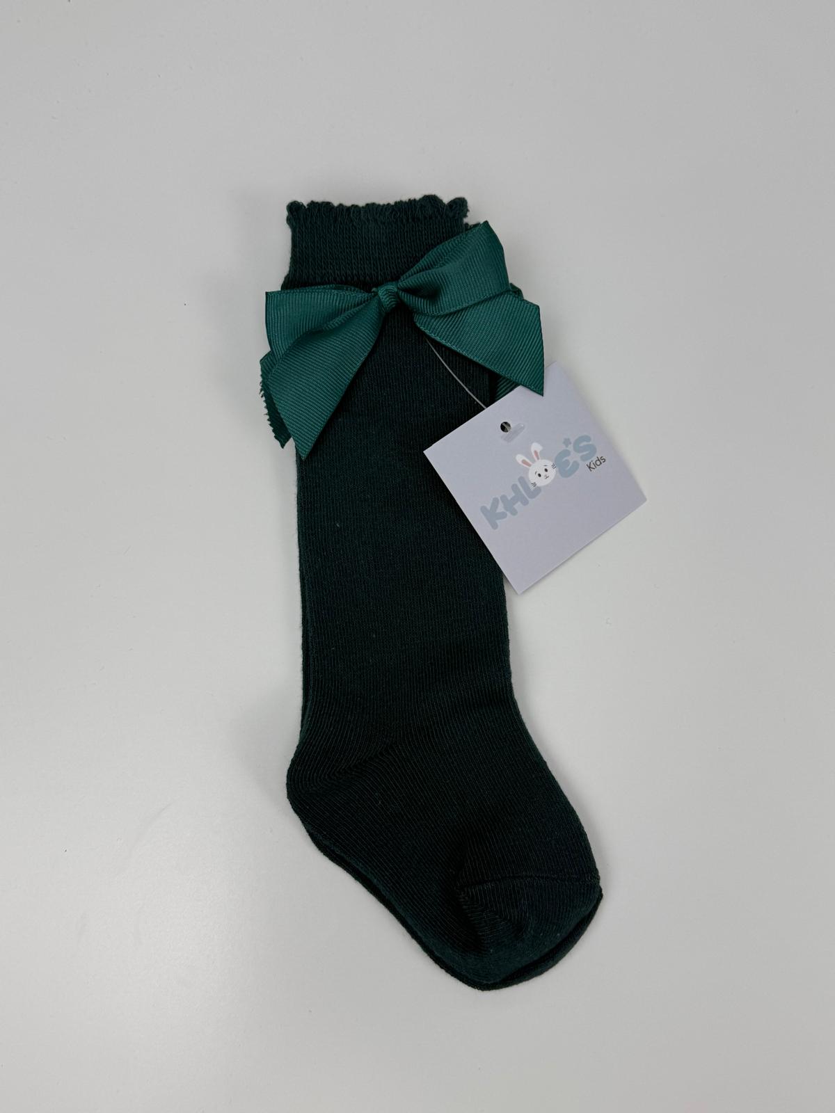 Black sock with a green bow and a tag on a light gray background